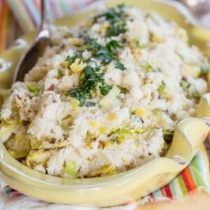 Cauliflower Colcannon garnished with parsley in a yellow serving dish.