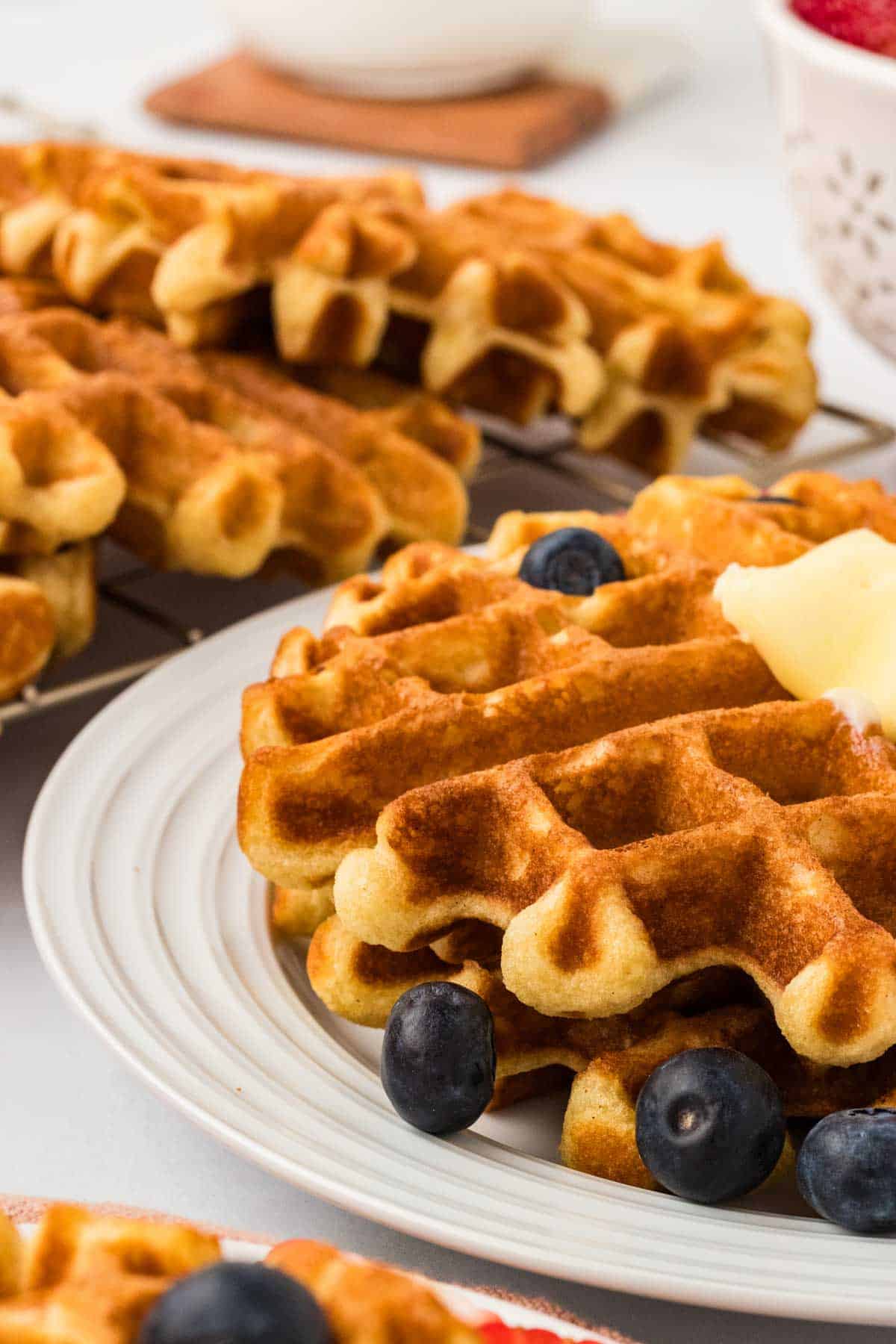 A plate of gluten free buttermilk waffles with more n the background