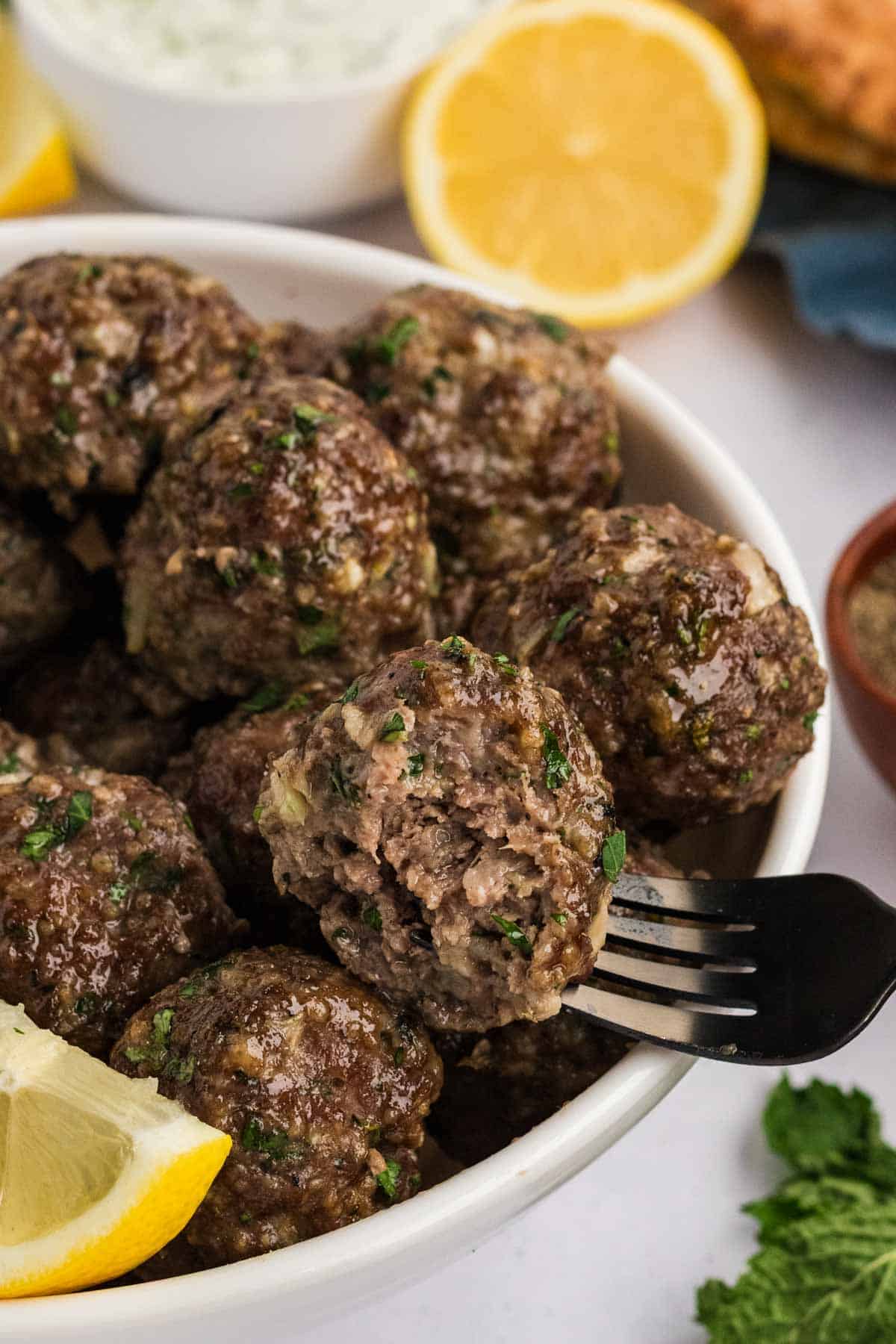 A fork in a Gluten Free Greek Meatballs in a bowl