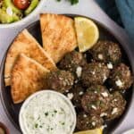 Overhead view of a black plate of Greek meatballs with pita and tzatziki