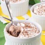 A spoon scooping Irish cream mousse and fudge out of a ramekin.