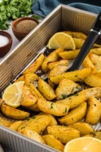 A spoon stirring Greek lemon potatoes in a pan