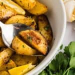 A spoon in a bowl of Greek potatoes