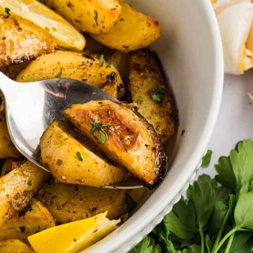 A spoon in a bowl of Greek potatoes