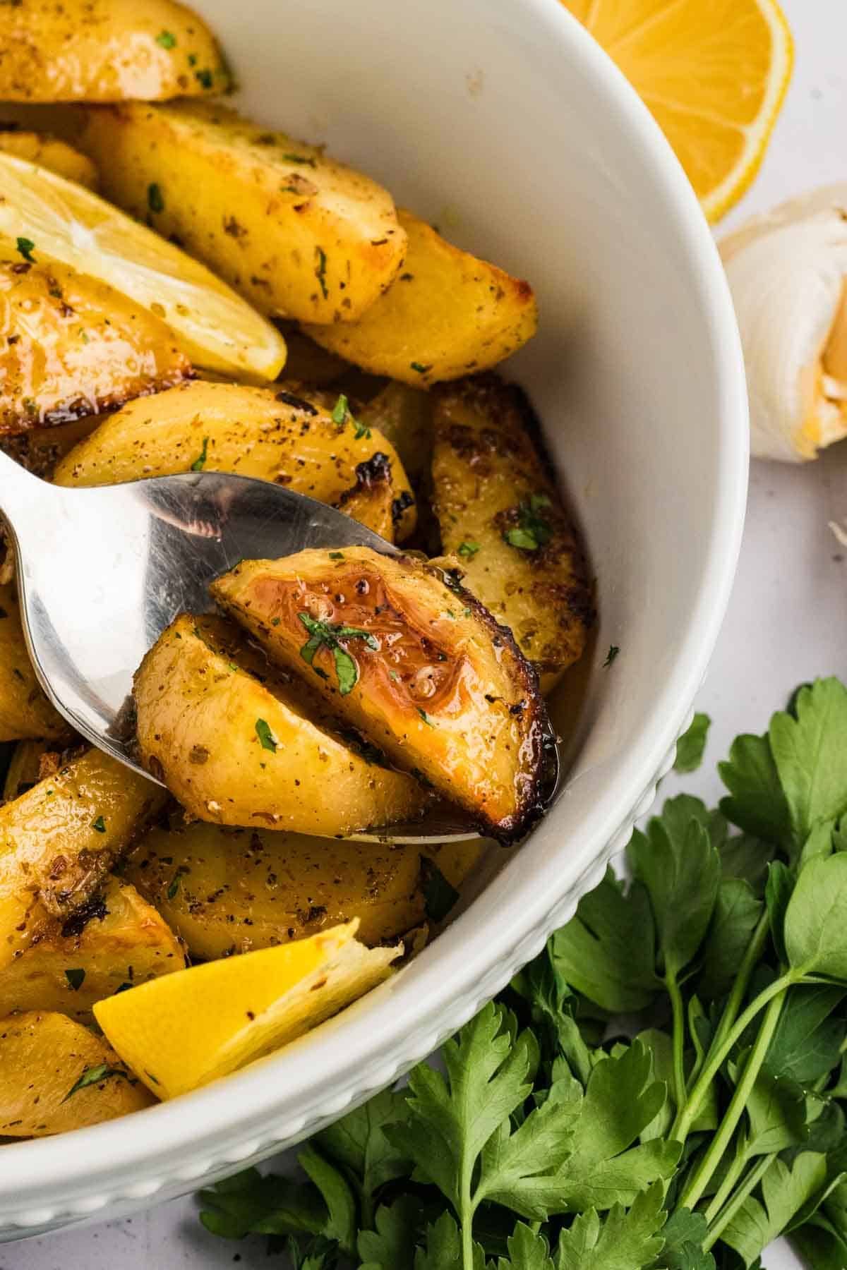 A spoon in a bowl of Greek potatoes