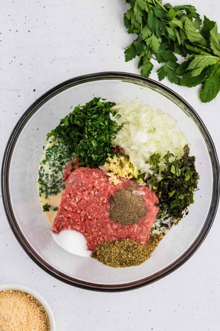 Ground beef, milk, herbs, and spices in a bowl.