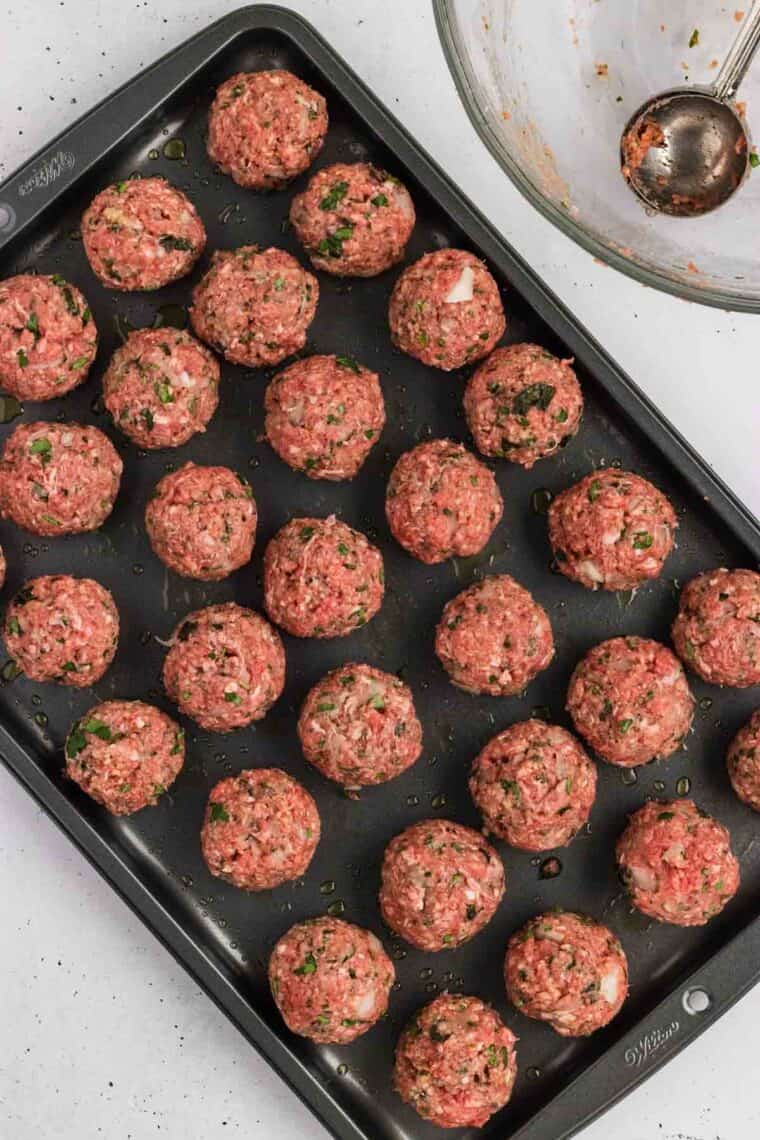 Unbaked Greek meatballs on a baking sheet