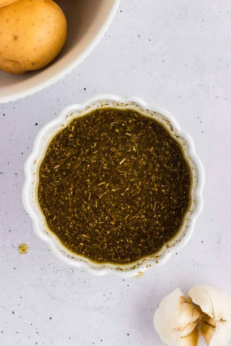 Potatoes are baked in a lemony, garlicky broth until golden on the outside and soft on the inside in this Greek Potatoes recipe. The herby lemon broth mixture in a bowl