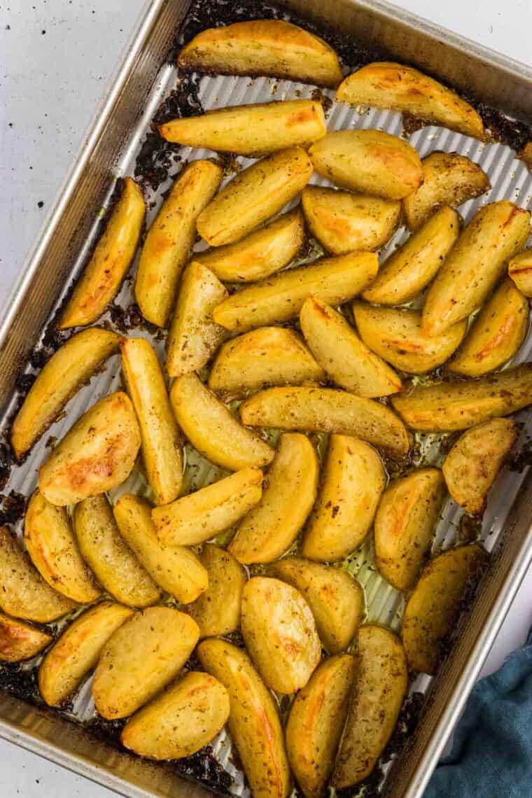 Potatoes are baked in a lemony, garlicky broth until golden on the outside and soft on the inside in this Greek Potatoes recipe. Overhead view of Greek potatoes in a baking dish