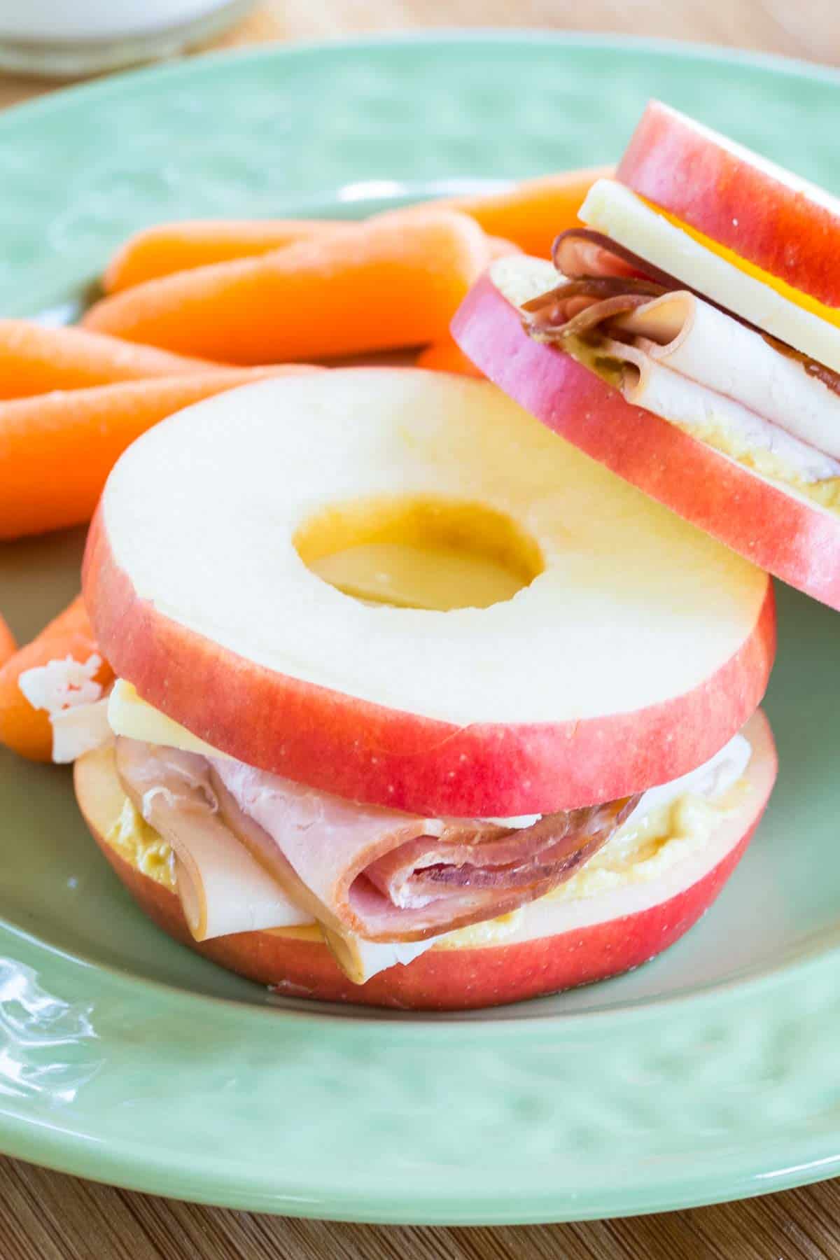 One apple sandwich leaning against another on a plate.
