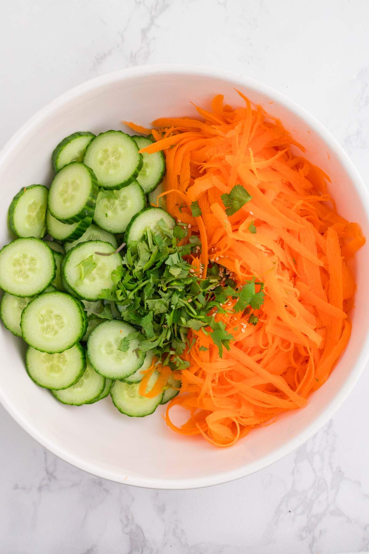 Cucumber slices and carrot ribbons in a bowl