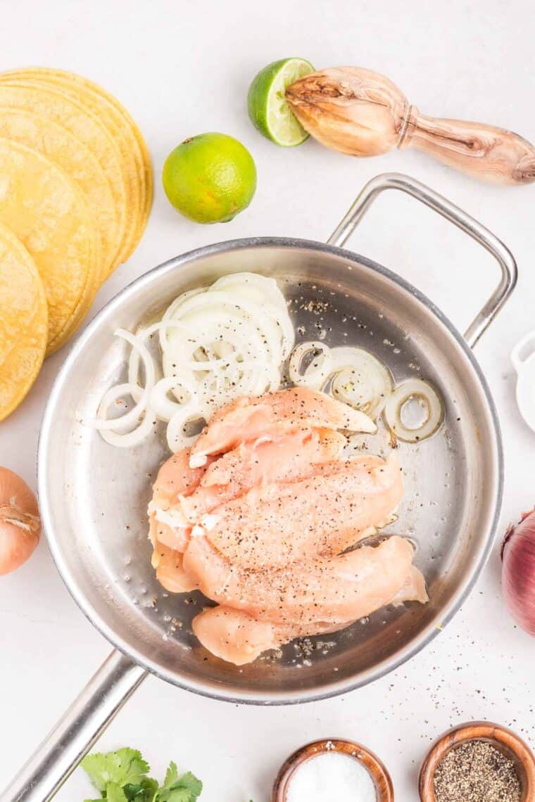 Sliced onions and chicken in a frying pan