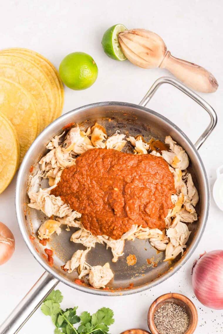Tinga sauce added to shredded chicken in a pan