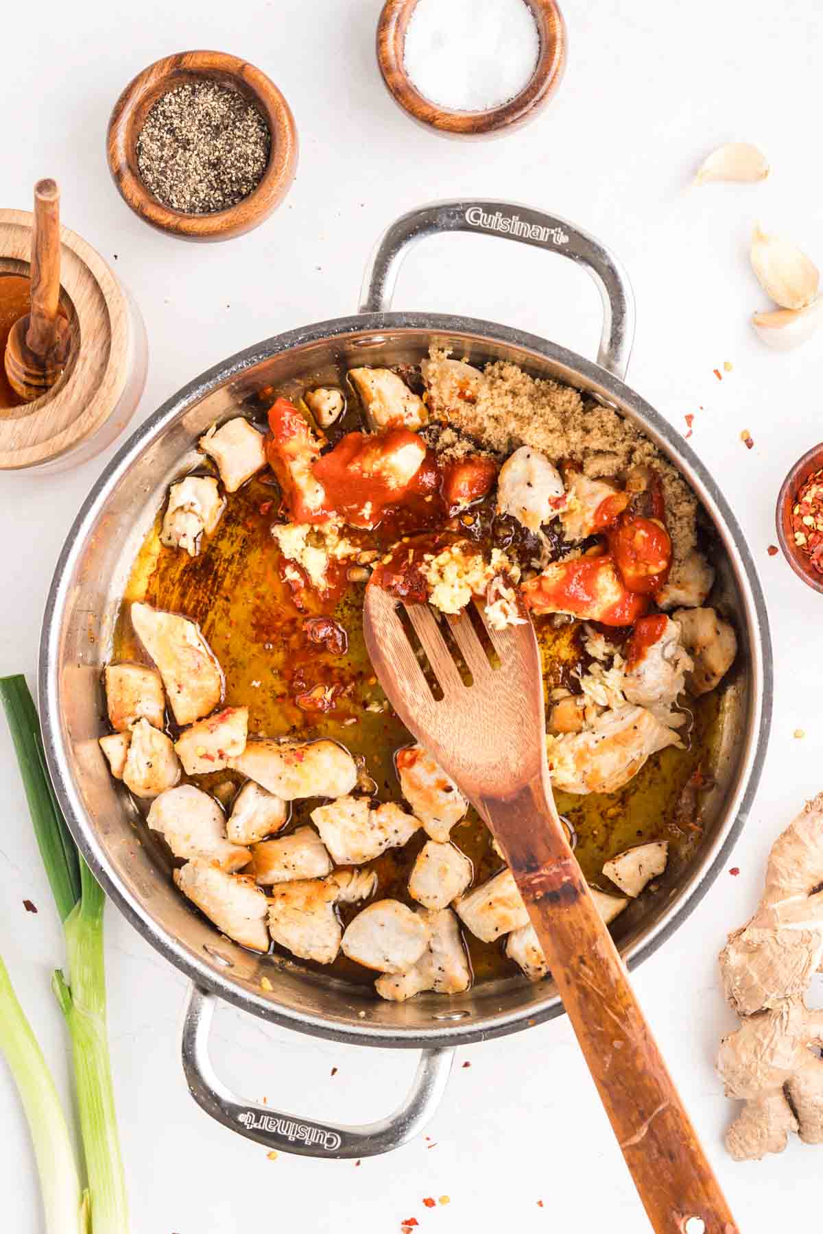 This easy sweet and spicy chicken is full of flavor, with honey, brown sugar, and sriracha. Ready in just 20 minutes! Stirring the chicken and sauce ingredients in a pan