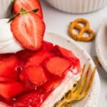 A slice of strawberry pretzel salad on a white plate with a gold fork