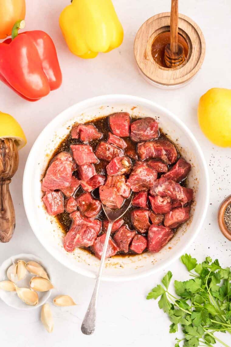 Chunks of sirloin are marinated then threaded onto skewers with onions, bell peppers, and mushrooms to make these beef kebabs. Pieces of steak in a bowl of marinade