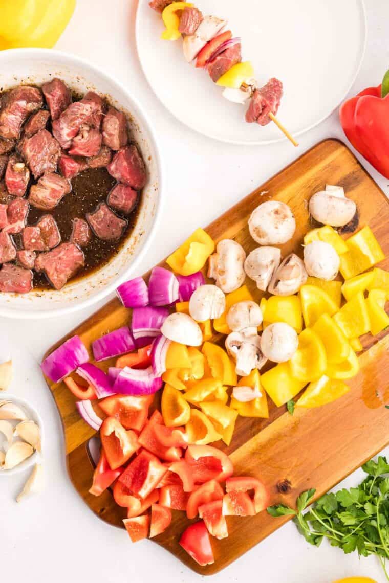 Chunks of sirloin are marinated then threaded onto skewers with onions, bell peppers, and mushrooms to make these beef kebabs. Bell peppers, onion, and mushrooms on a cutting board