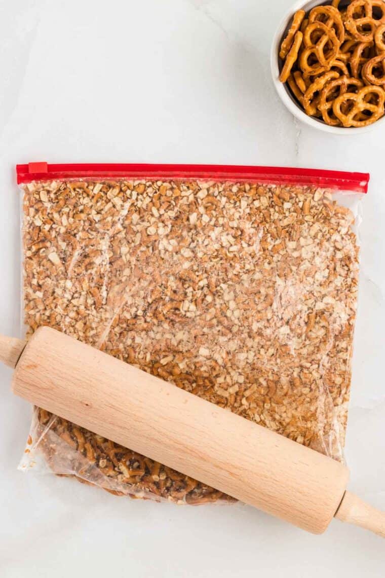 Pretzel crumbs in a ziplog bag with a rolling pin outside