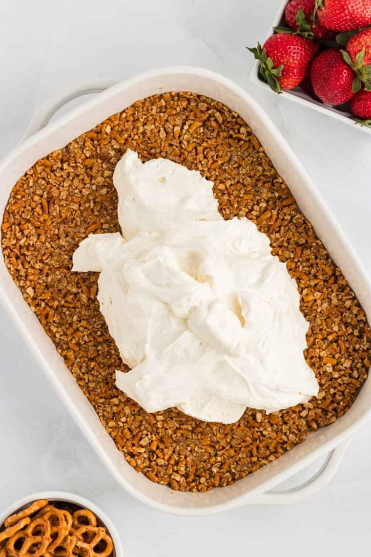 Cream cheese filling on top of pretzel crust in a pan
