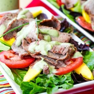 Mango steak salad with tomatoes and avocado ranch on a plate.