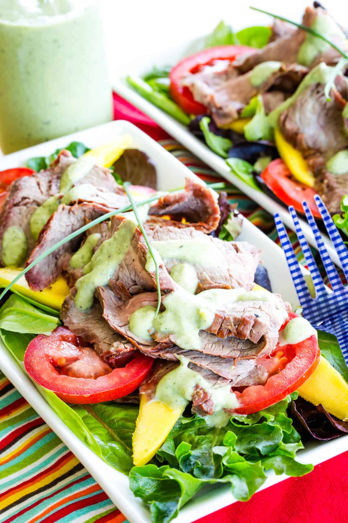 Two plates of grilled steak and mango salad.