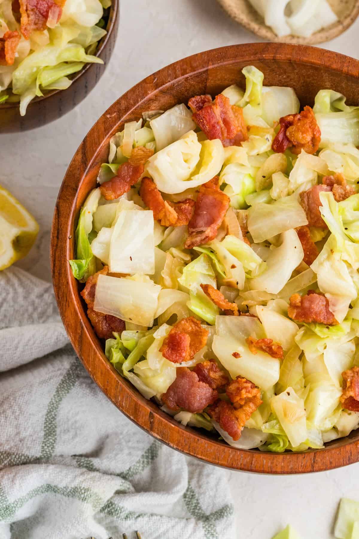 This easy Fried Cabbage recipe turns a handful of ingredients into a savory side dish perfect for busy weeknights & potlucks. Close overhead view of a bowl with fried cabbage and bacon