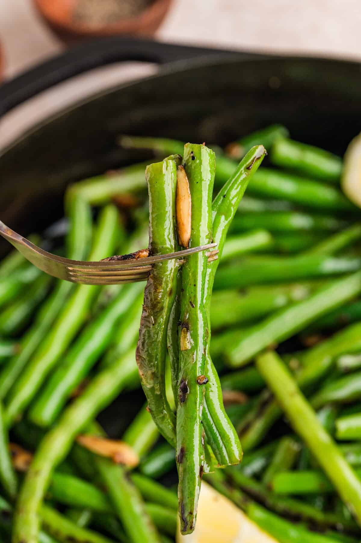 Garlic green beans on a fork above a skillet