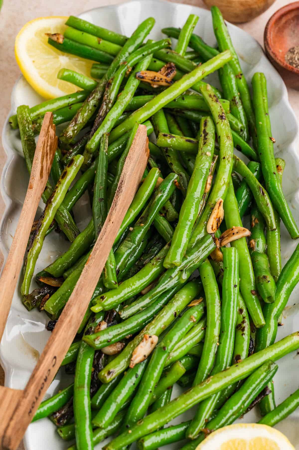 Tongs stirring garlic green beans