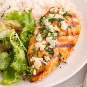 Grilled buffalo chicken on a plate with salad and rice