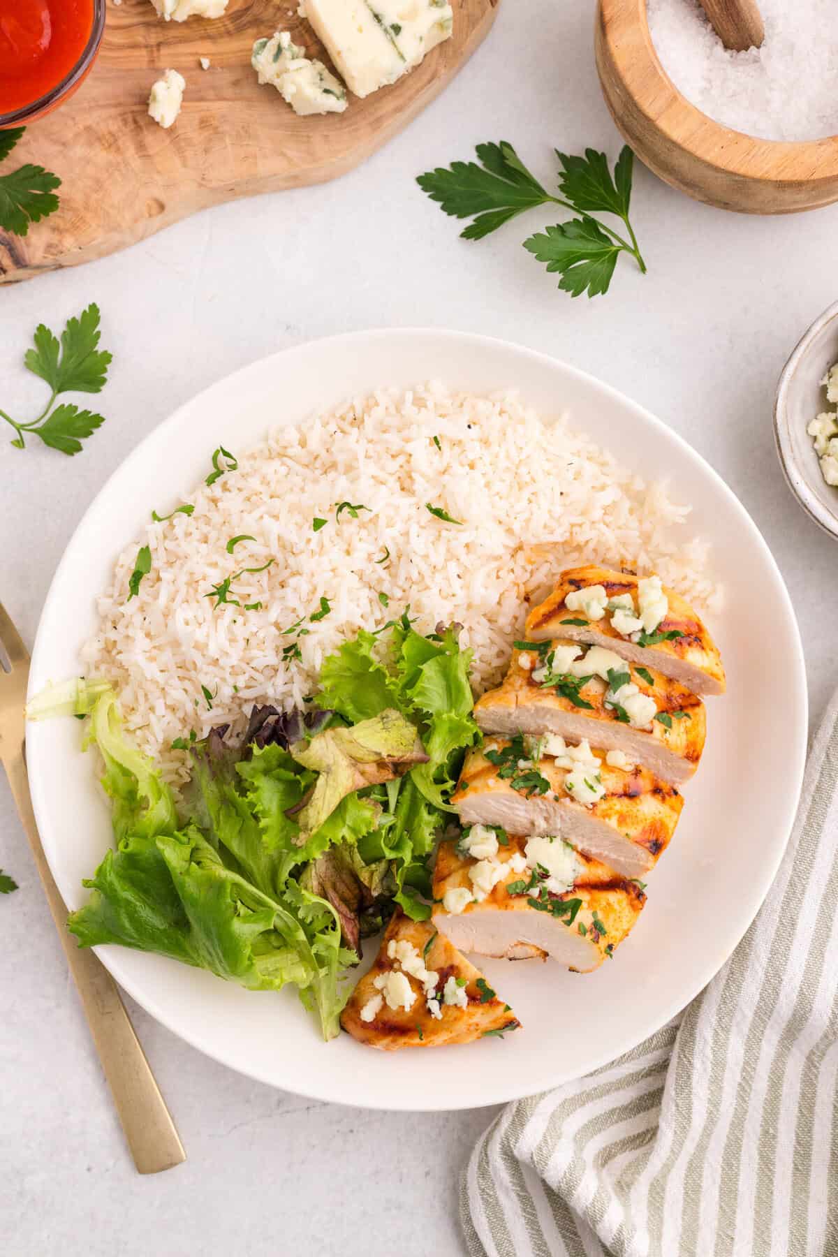 Overhead view of sliced grilled buffalo chicken on a plate with rice and lettuce