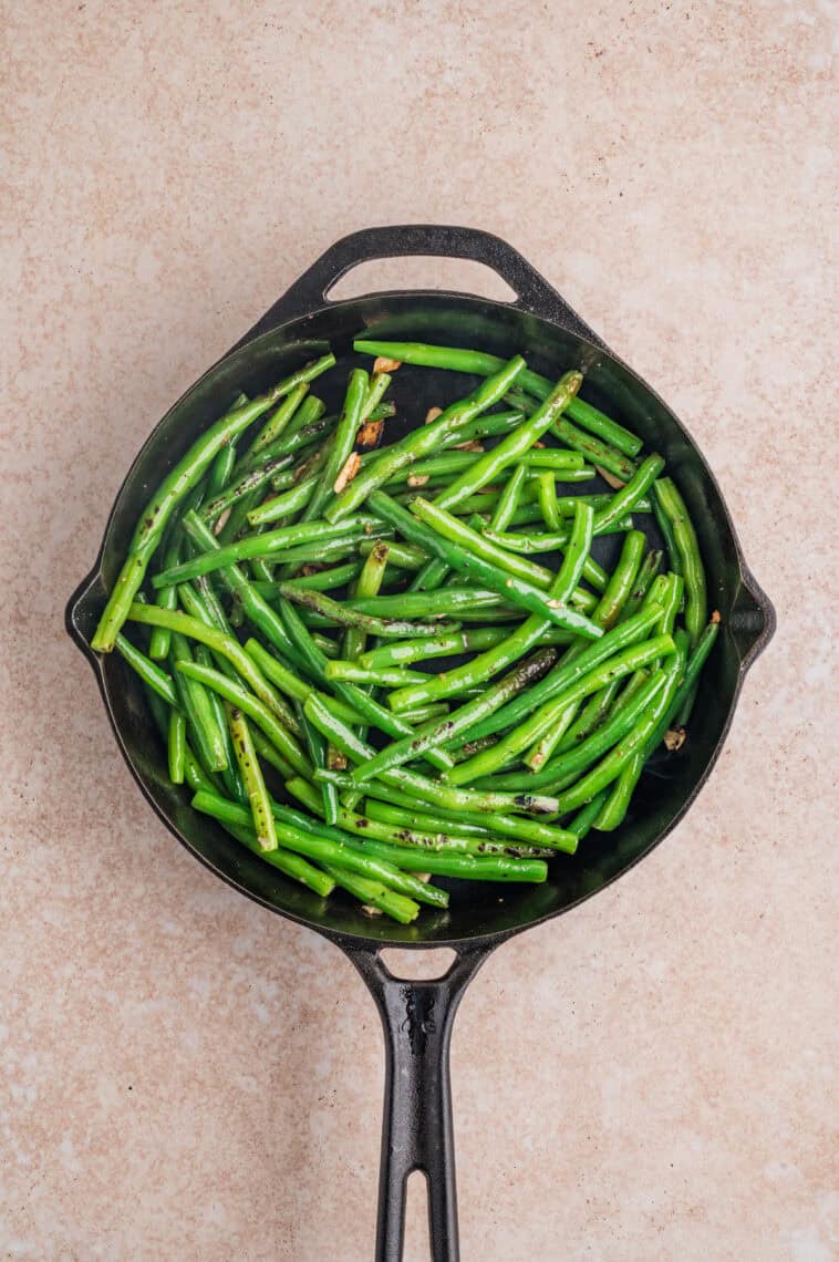 Cooked green beans and garlic in a skillet