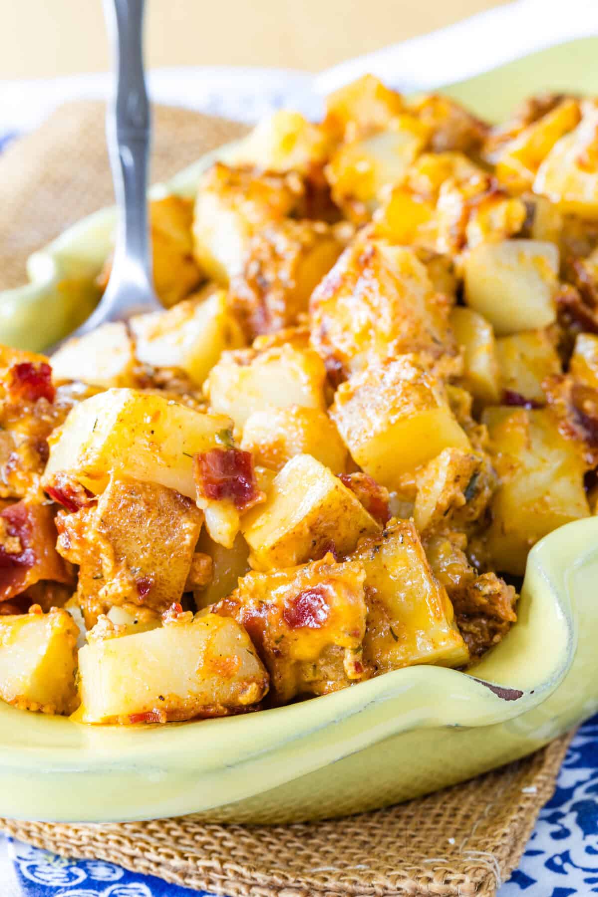 A spoon resting in a dish of cheesy ranch roasted potatoes.