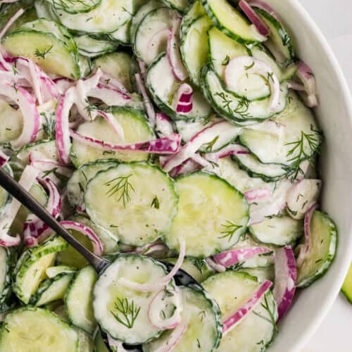 Overhead view of a white bowl of creamy cucumber salad