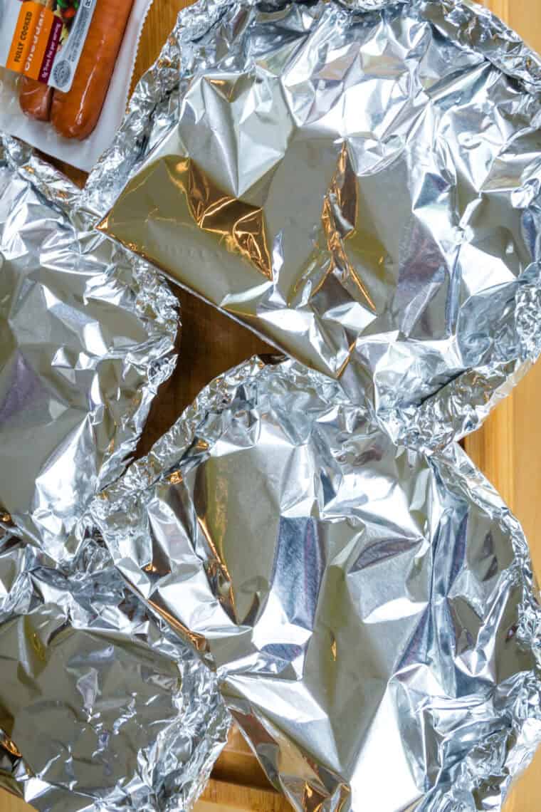 Wrapped up foil packs on a cutting board.