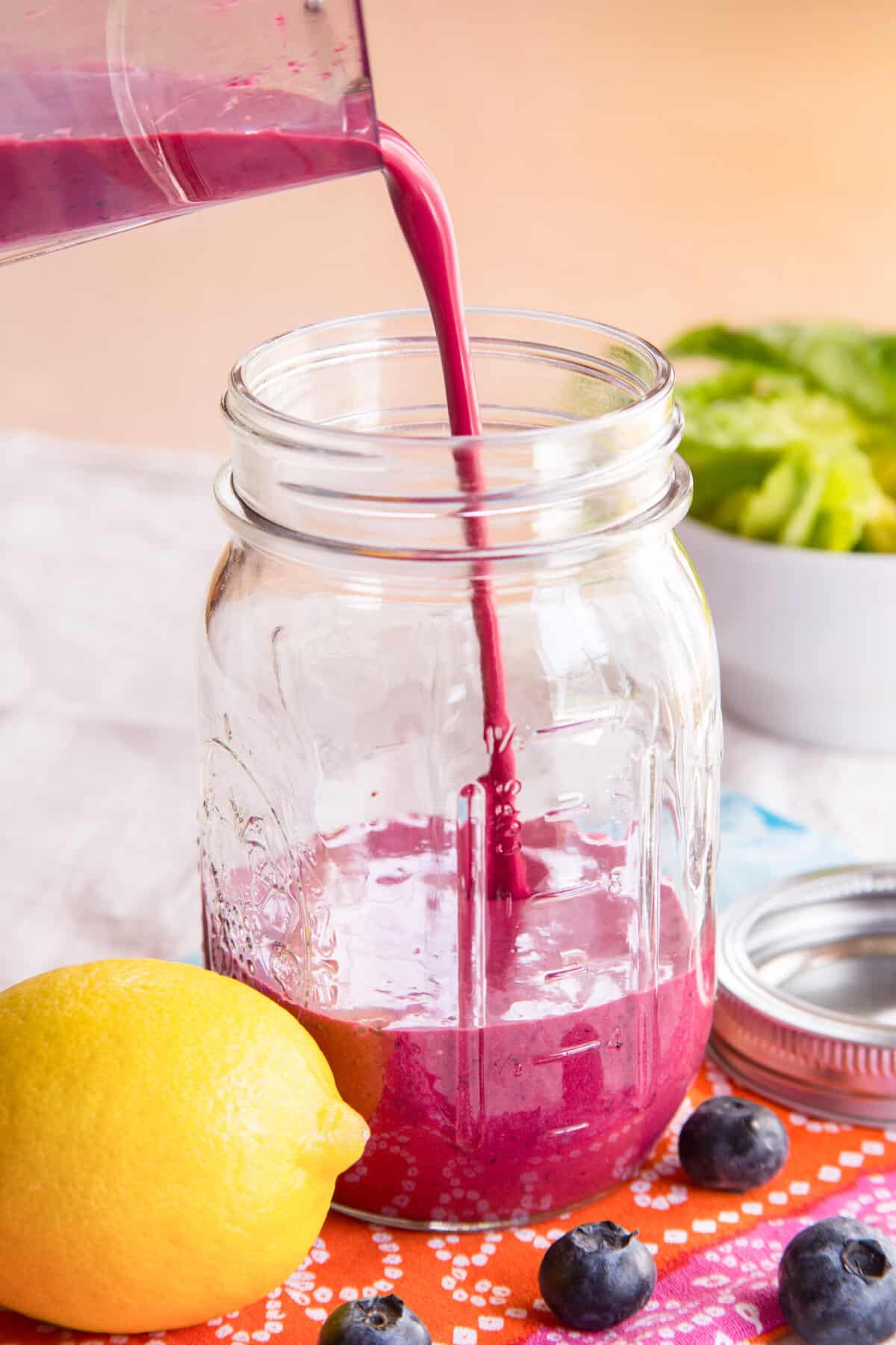 Salad dressing being poured from a blender into a jar.