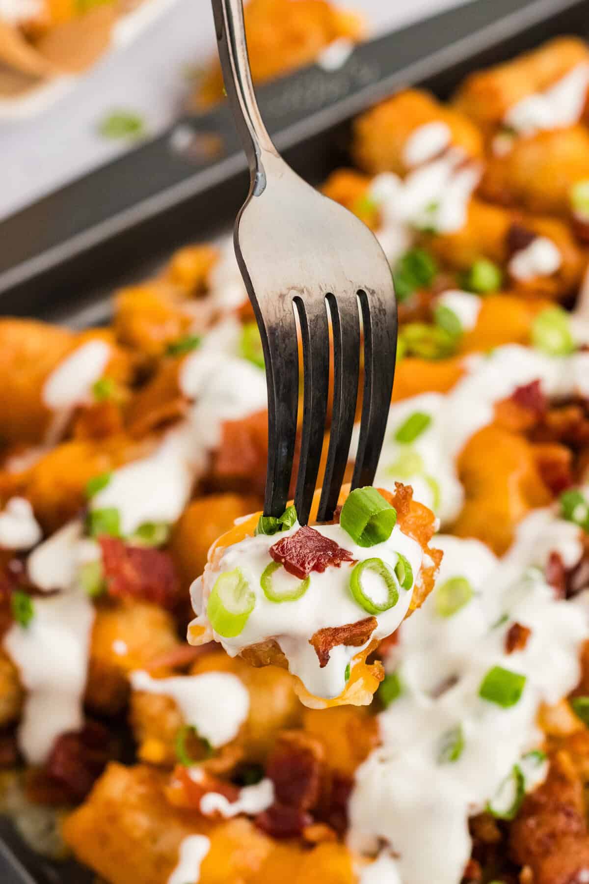 A fork in a bite of loaded tater tots