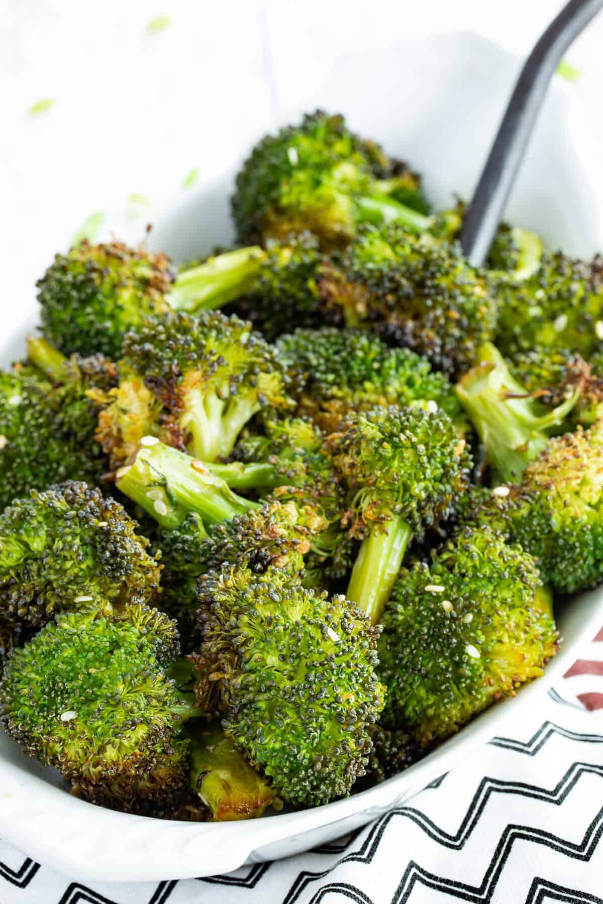 A closeup of a dish of maple roasted broccoli with sesame seeds.