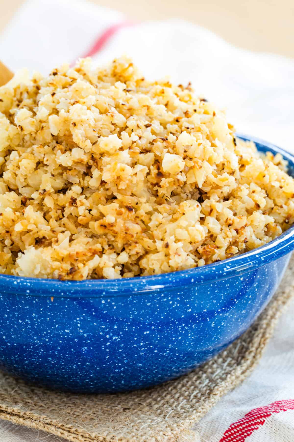 A blue speckled bowl of brown butter cauliflower rice.