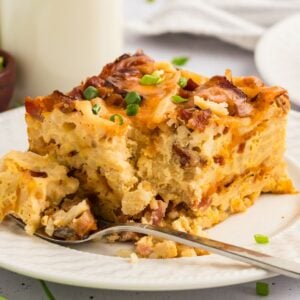 A slice of crockpot breakfast casserole with a fork on a white plate