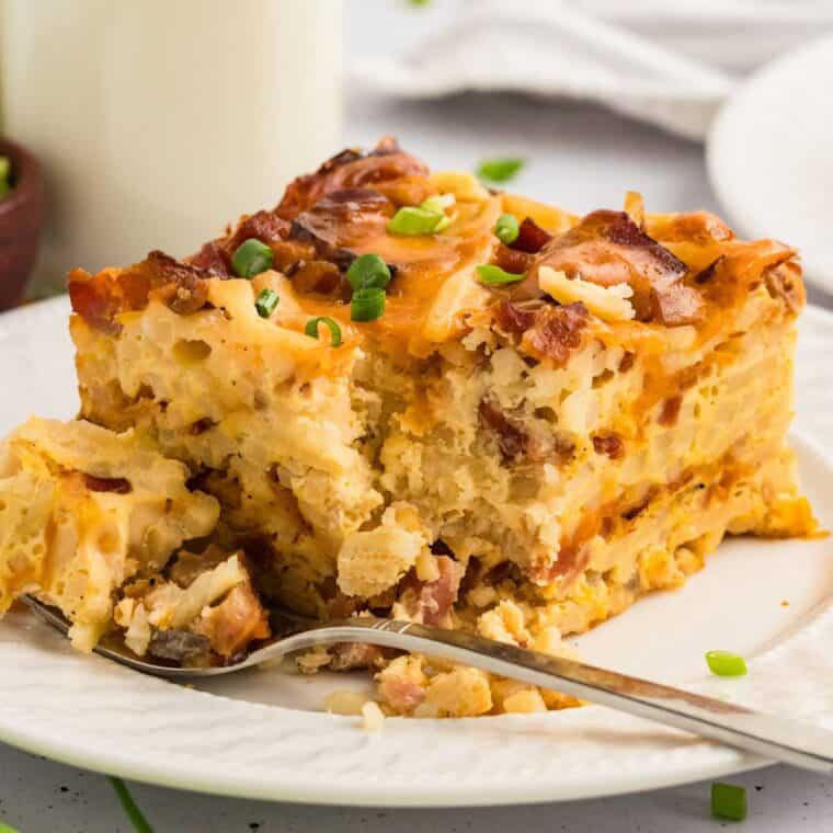 A slice of crockpot breakfast casserole with a fork on a white plate