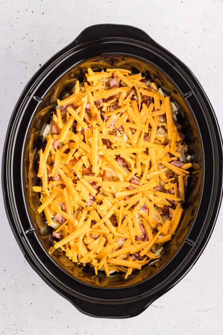 Shredded cheese on top of hashbrowns in a crockpot