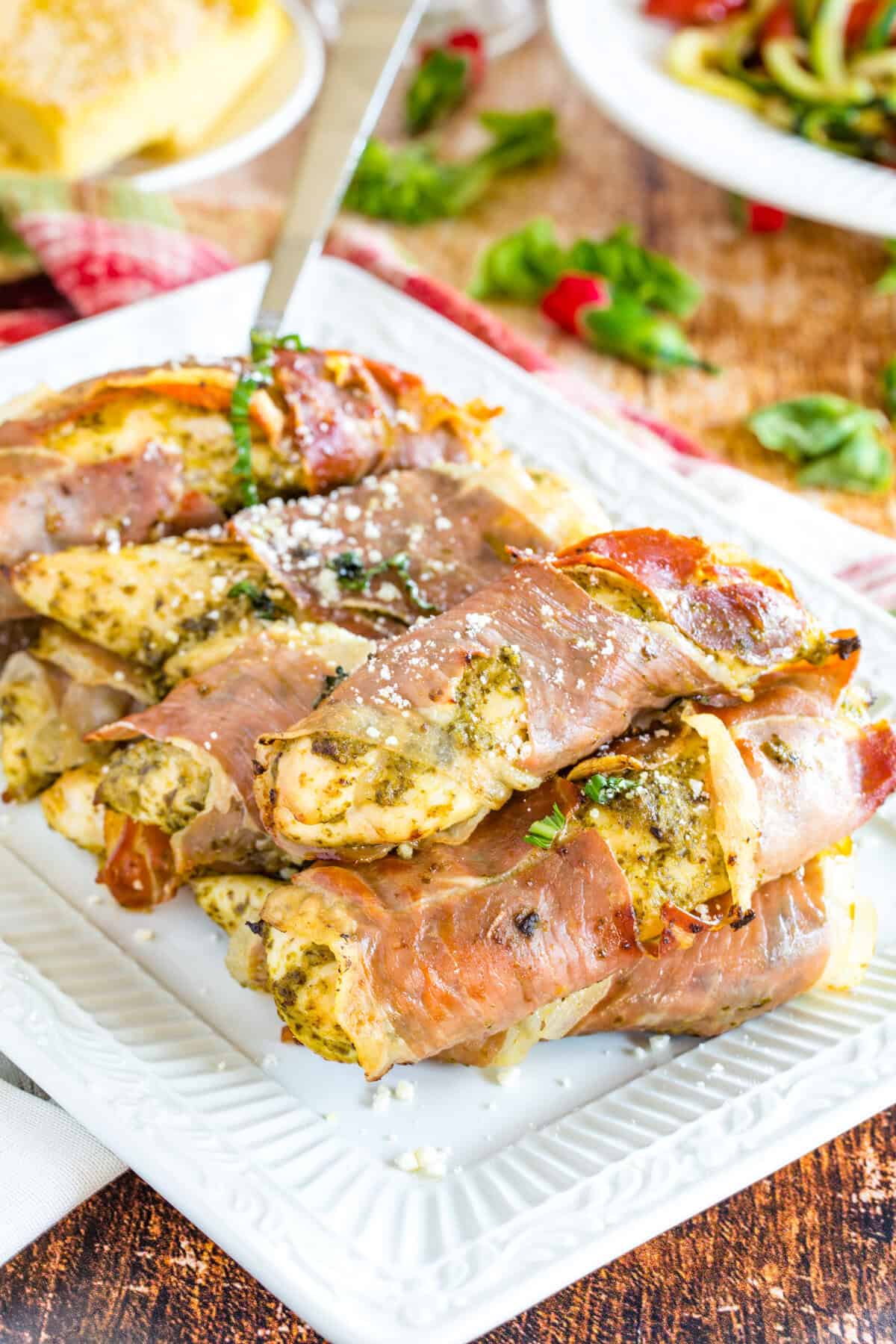 A white platter of prosciutto-wrapped chicken.
