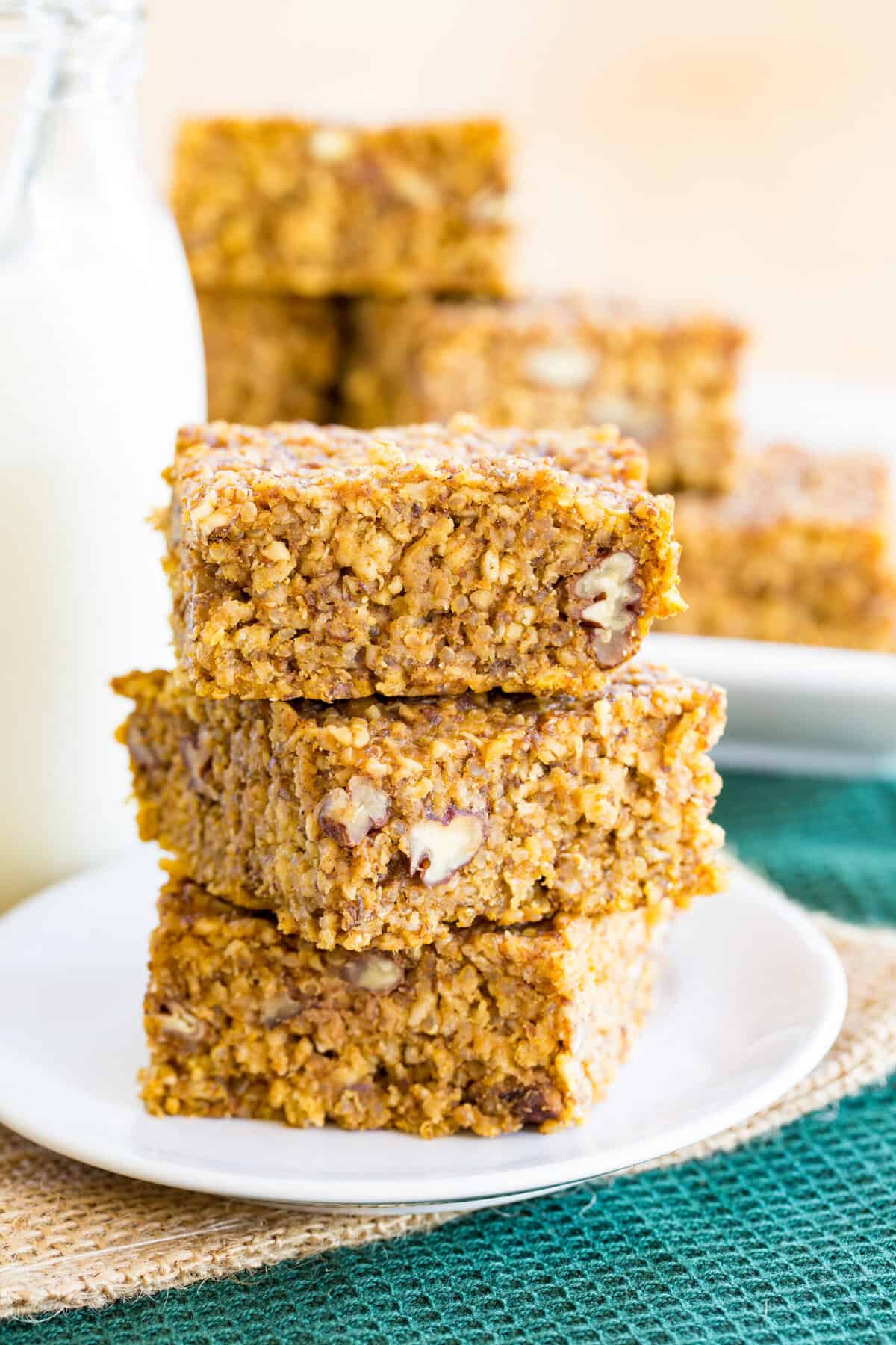 Pumpkin breakfast bars made with oats and quinoa in a stack on a plate.