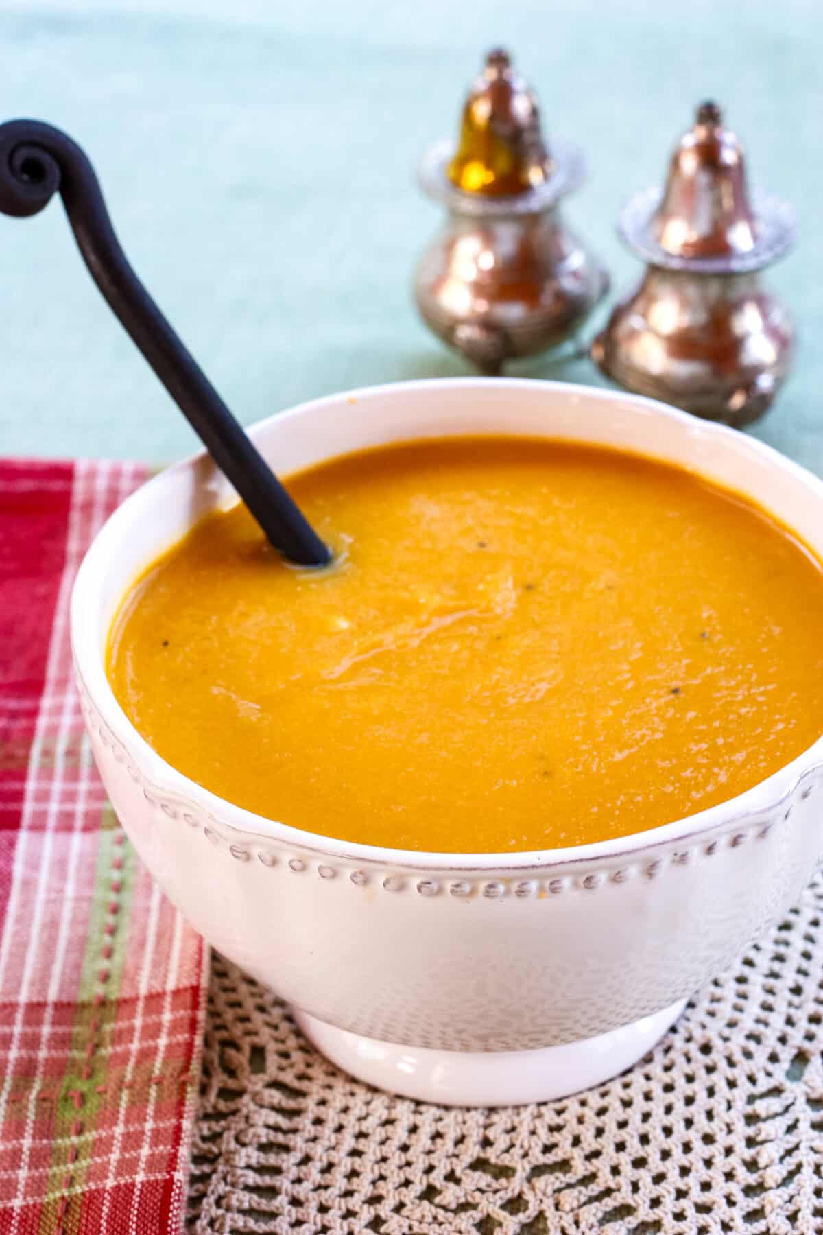 A spoon in a bowl of cheddar cheese butternut squash soup.