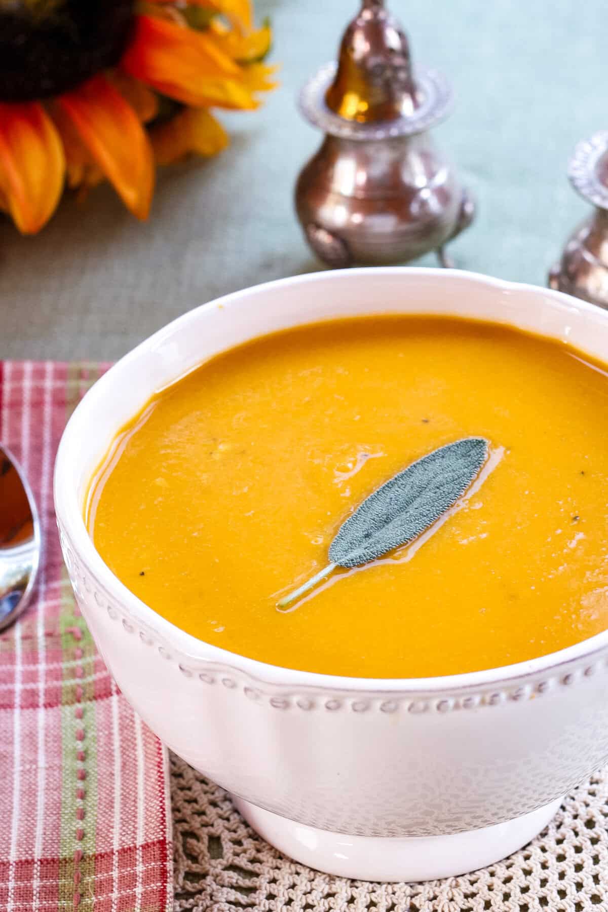 A closeup of cheesy butternut squash soup in a white bowl.