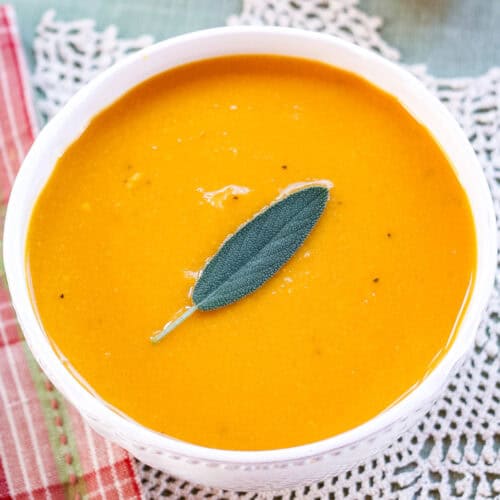 A birdseye view of a bowl of butternut squash soup garnished with a sage leaf.
