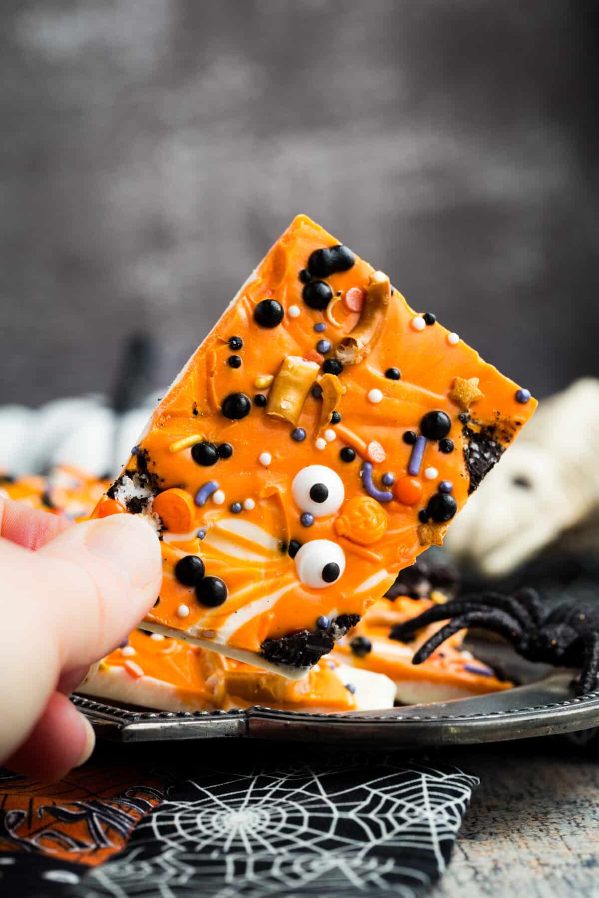A hand holding a piece of gluten free Halloween bark.