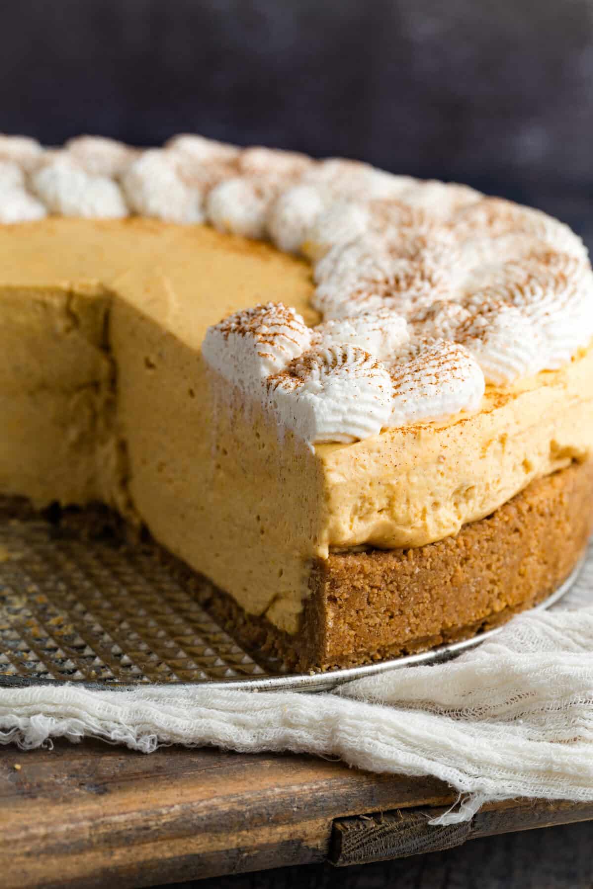 With a graham cracker crust and fluffy pumpkin filling, this gluten free no-bake pumpkin cheesecake is an easy fall dessert. A gluten free no bake pumpkin cheesecake with a slice missing