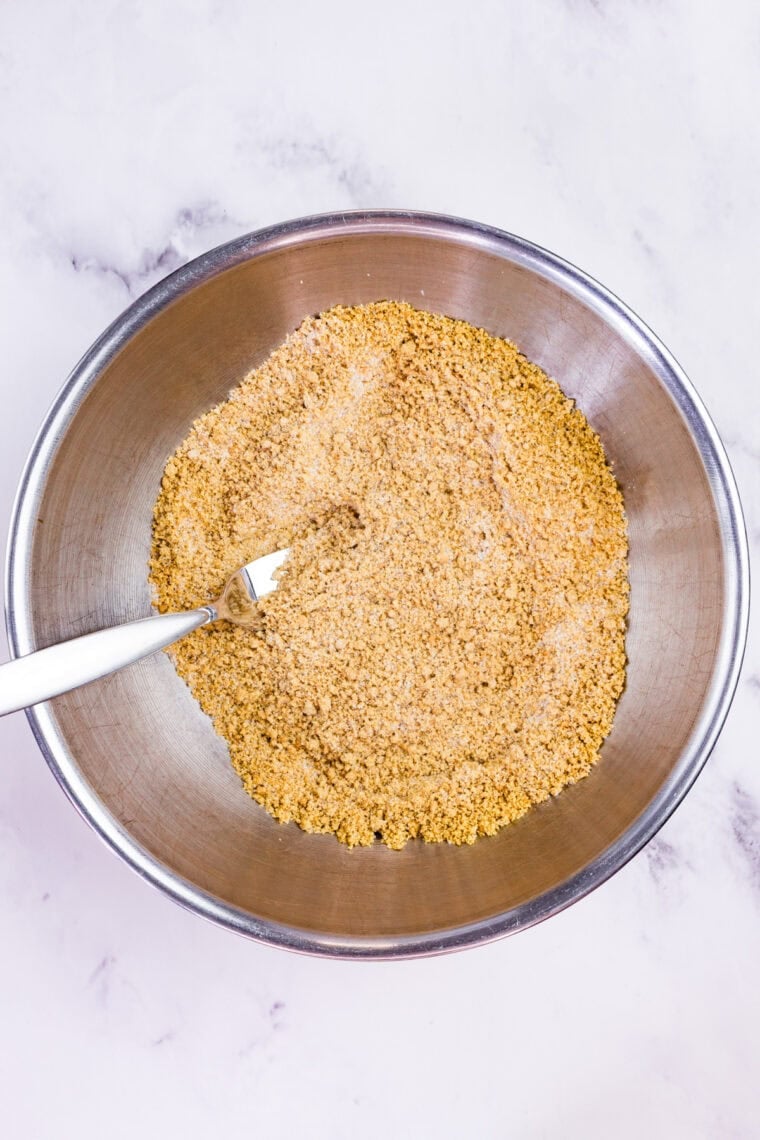 With a graham cracker crust and fluffy pumpkin filling, this gluten free no-bake pumpkin cheesecake is an easy fall dessert. Stirring graham cracker crumbs, sugar, and cinnamon in a bowl